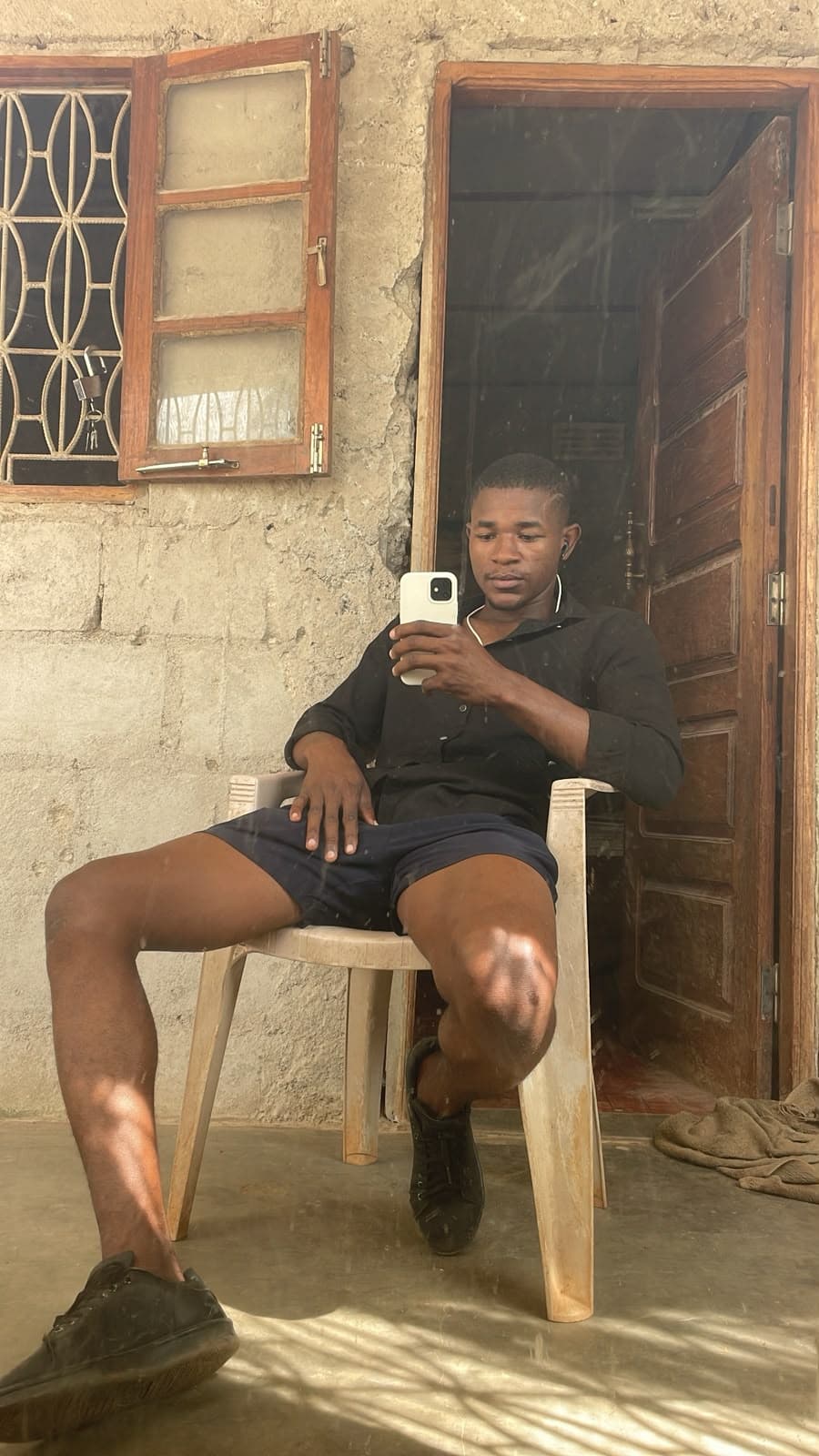 Michael sentado numa cadeira de plástico à porta de casa