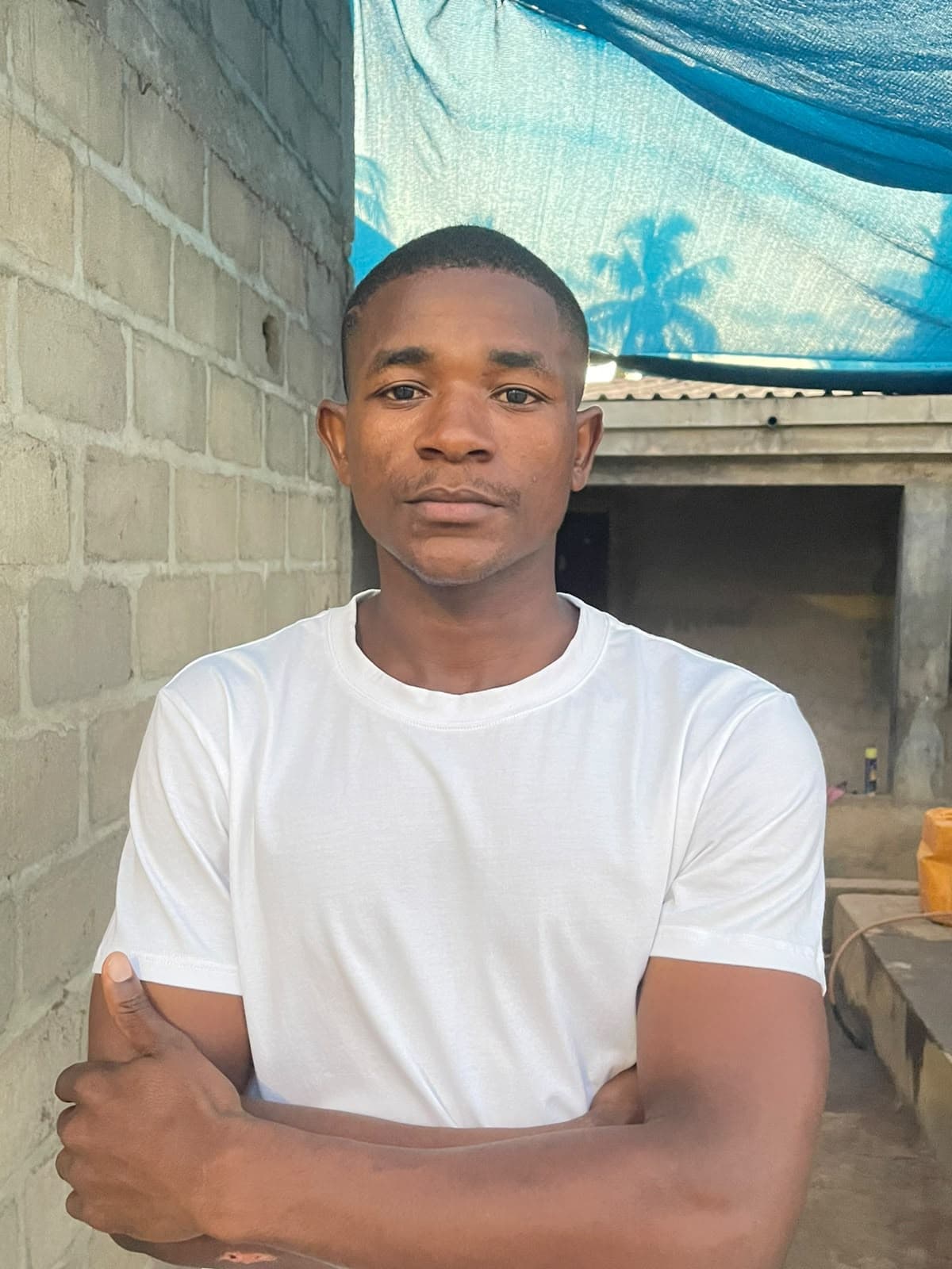 Michael Tarige, de braços cruzados, em frente a uma parede de blocos em Moçambique